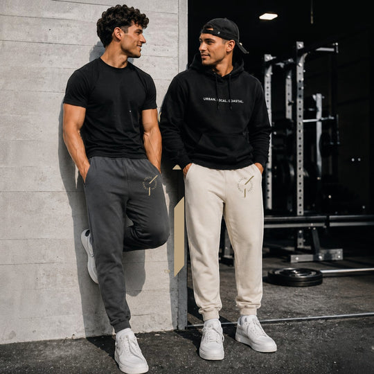 Two men in area 609 heavyweight fleece track pants in shadow and bone colors with embroidered Founders Mark logo